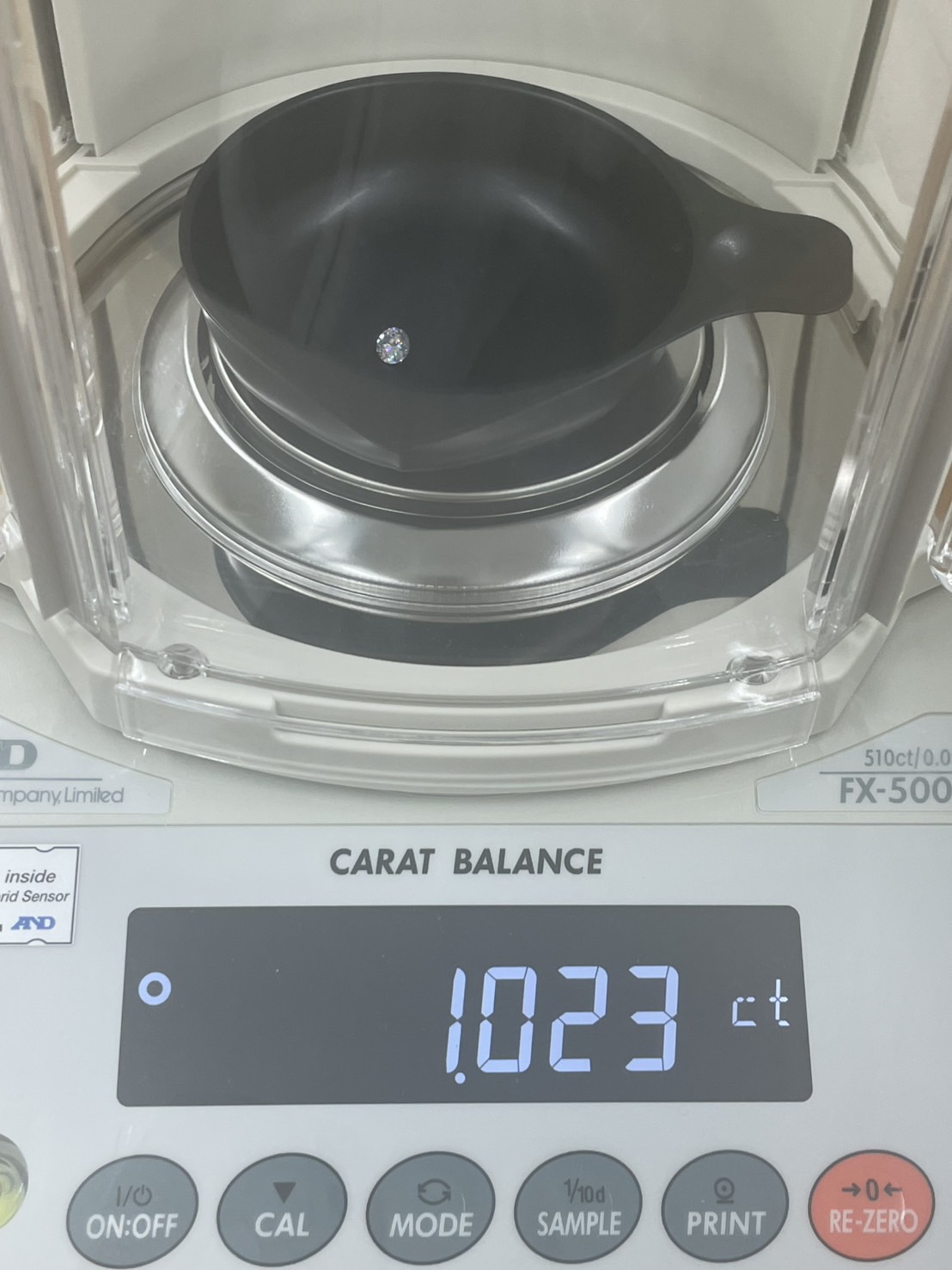 カラット測定器でカラーレスのラウンドカットのメモリアルダイヤモンドを鑑定している様子
